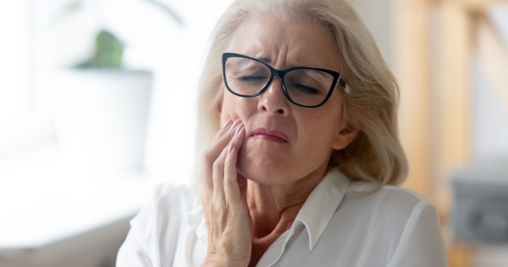 Hurt senior female worker in glasses feel stressed suffering from severe toothache at workplace, unhappy aged woman employee in glasses feel bad stressed having teeth pain, need dental treatment

