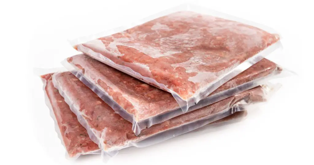Multiple frozen meat packages in a pile, vacuum sealed. Ground chicken inclusive backs, necks, liver and heart. Concept for raw food diet for cats, dogs and pets. Isolated on white.
