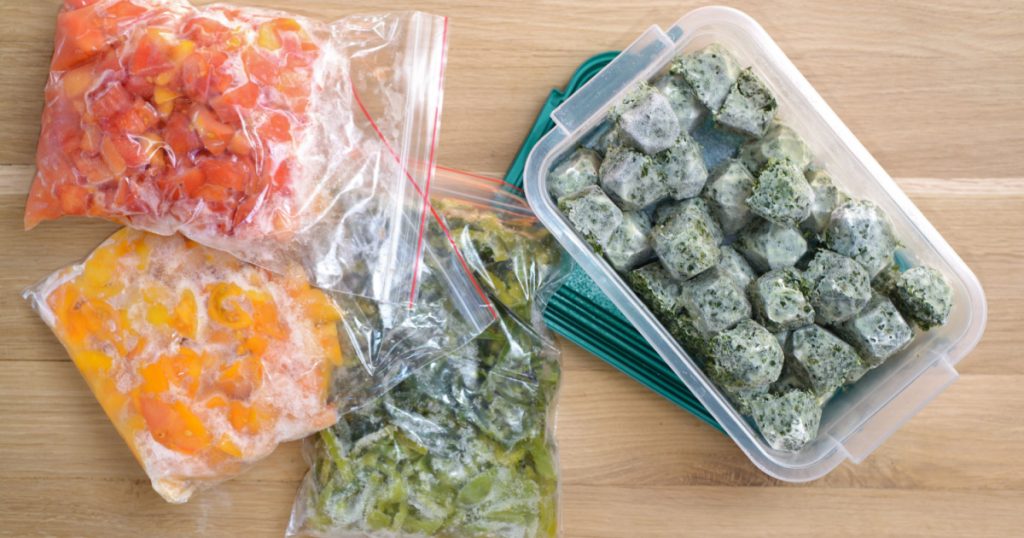 Frozen vegetables on cutting board and plastic bags. top view
