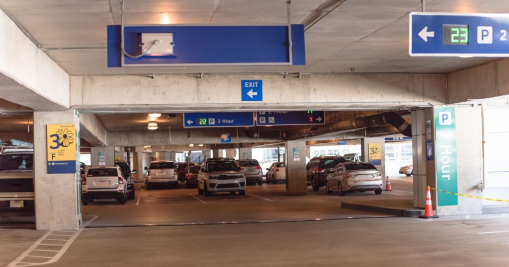 2 hour parking overhead neon sign at indoor airport parking lot displays number of available parking spaces. Available empty spots display counter information
