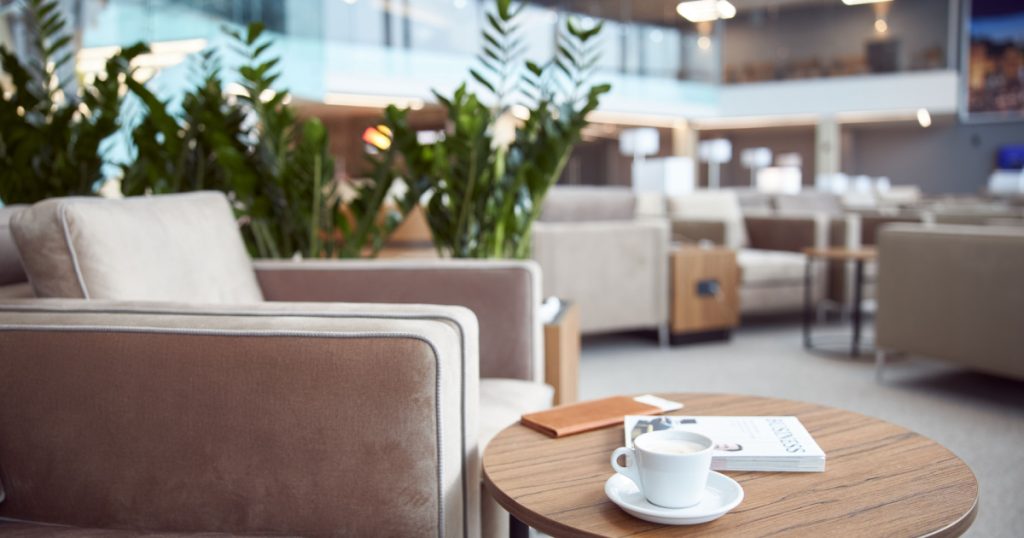 Round desk with business literature, cup of hot drink and wallet at airport waiting room stock photo
