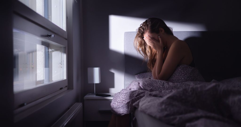 Sad depressed woman in bed. Lonely person with stress, insomnia and trouble sleeping. Anxiety, sorrow, solitude, grief or panic. Restless tired and desperate girl crying with emotion.

