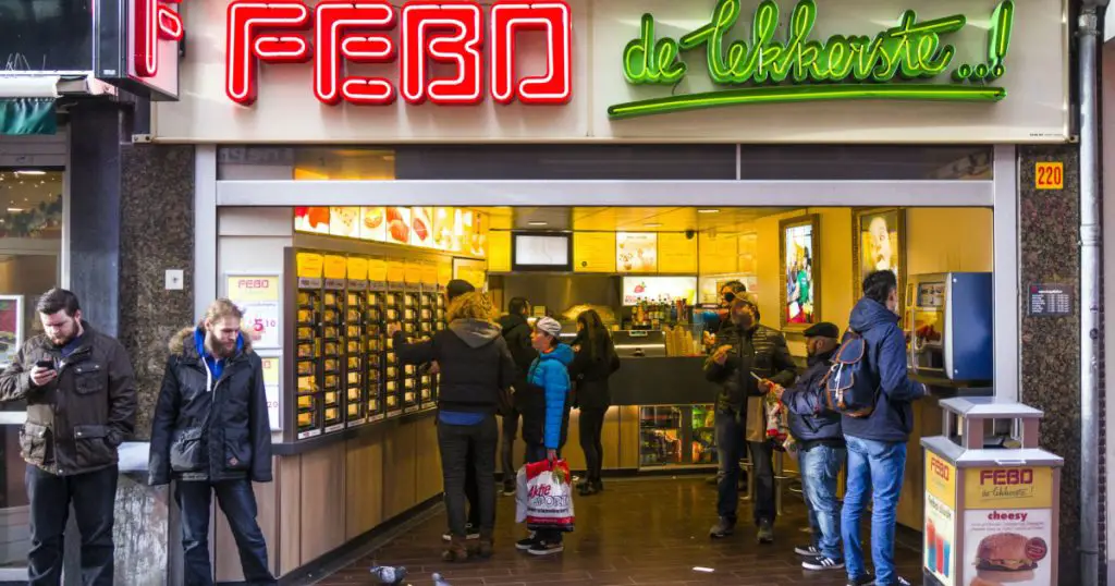 Amsterdam, Holland, January 11, 2015. Branch of the famous Dutch Febo snackbar chain with people buying and eating fast food
