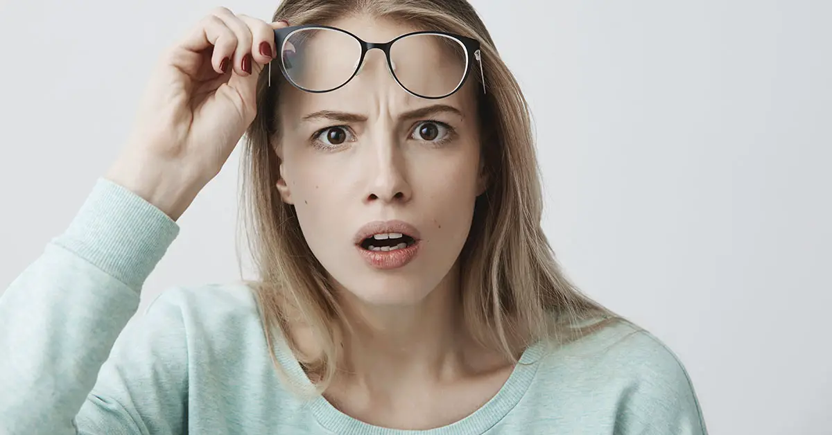 woman lifting glasses to get a better look at something