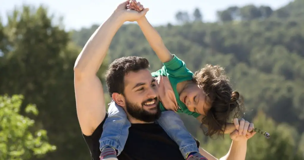 Bearded father and baby girl playing outdoors. Happy image of single father.