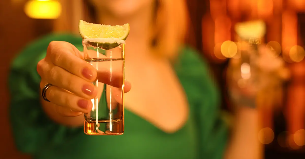 woman handing you a shot of tequila with lime