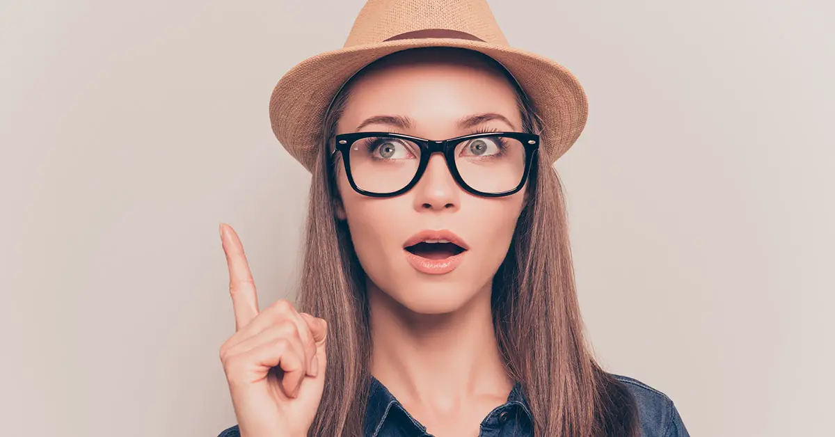 woman wearing a hat point finger up looking surprised