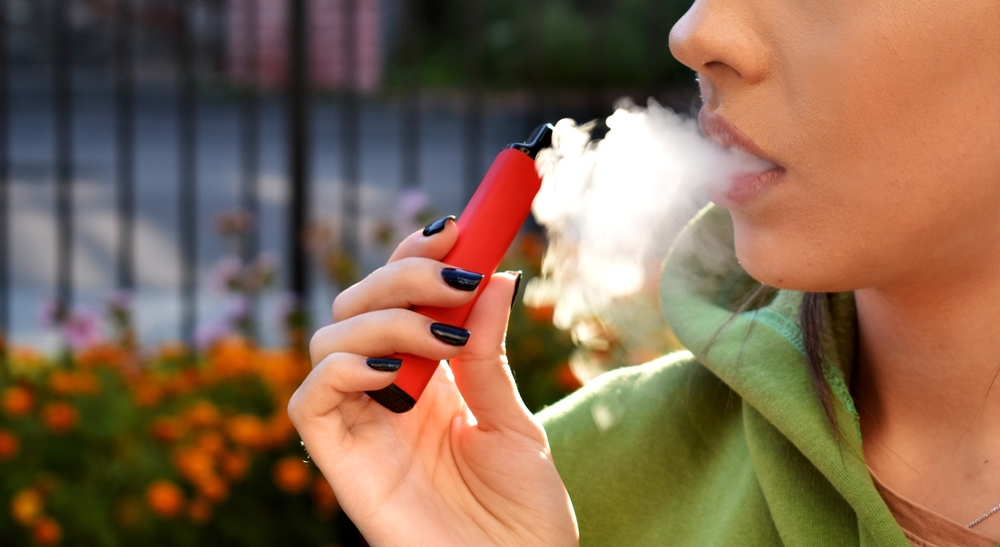 beautiful women smoke electronic cigarette in street