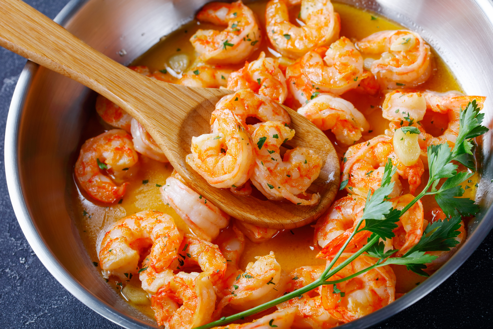 Keto diet dish shrimp scampi with garlic and butter sauce sprinkled with parsley, on a skillet on concrete background, horizontal orientation, close-up