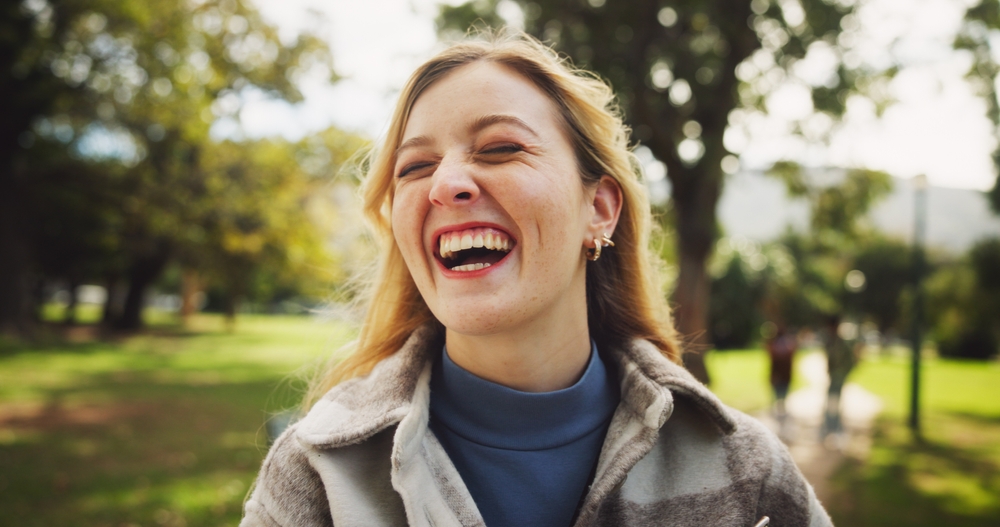 Female student, happy and laughing in park for study opportunity, knowledge and school with smile. Woman, excited and sunshine at campus, university or college for education, learning and scholarship