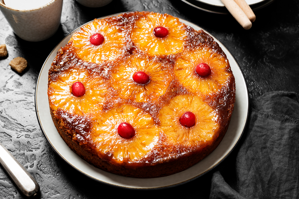 Homemade pineapple upside down pie with candied cranberry . Tropical dessert on black background .