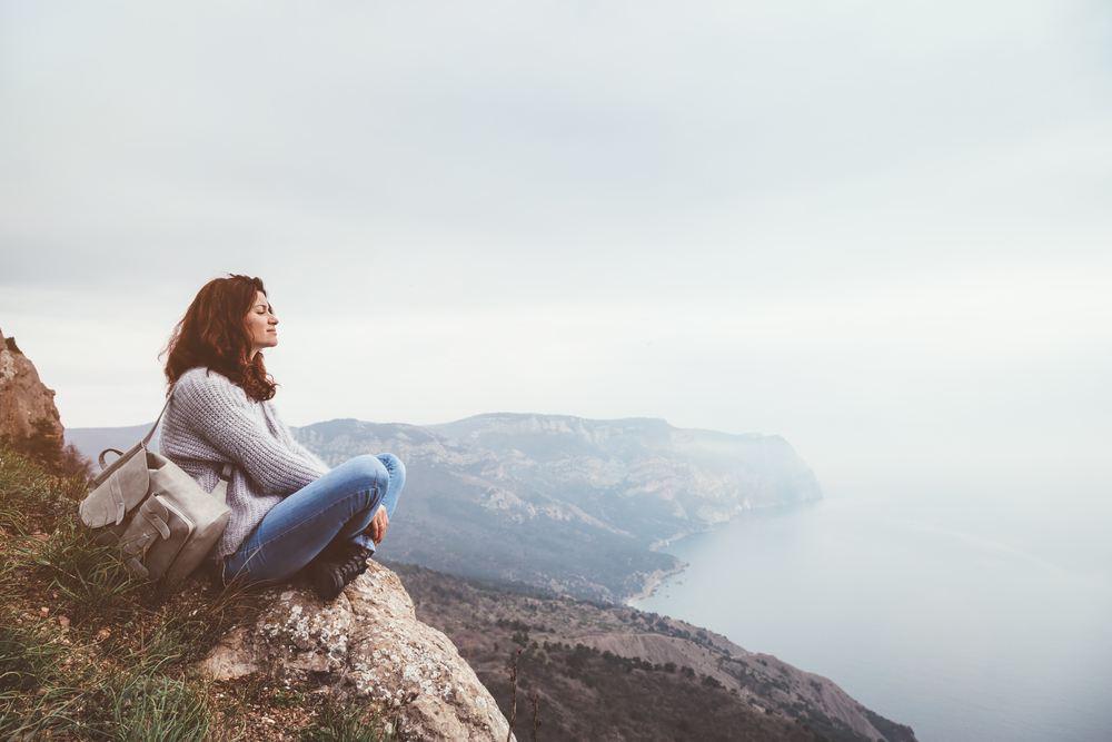 woman sitting on cliff
